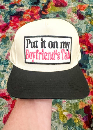 Cream snap back ball cap with a black bill and embroidered patch “Put it on my Boyfriend’s Tab” in Black and Hot Pink.