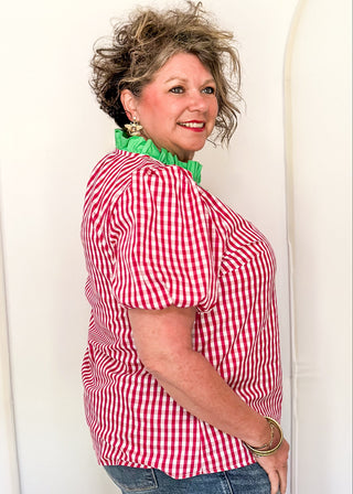 Women’s gingham blouse with decorative buttons and statement neckline detail.