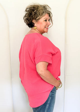 Solid pink textured blouse with a V-notch neckline, short sleeves