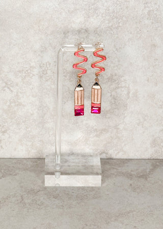 Pencil dangle earrings displayed on a stand 