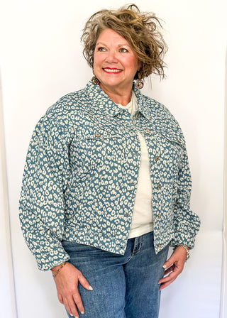Cropped denim jacket with a blue and white floral print, long sleeves, button-front closure, and chest pockets