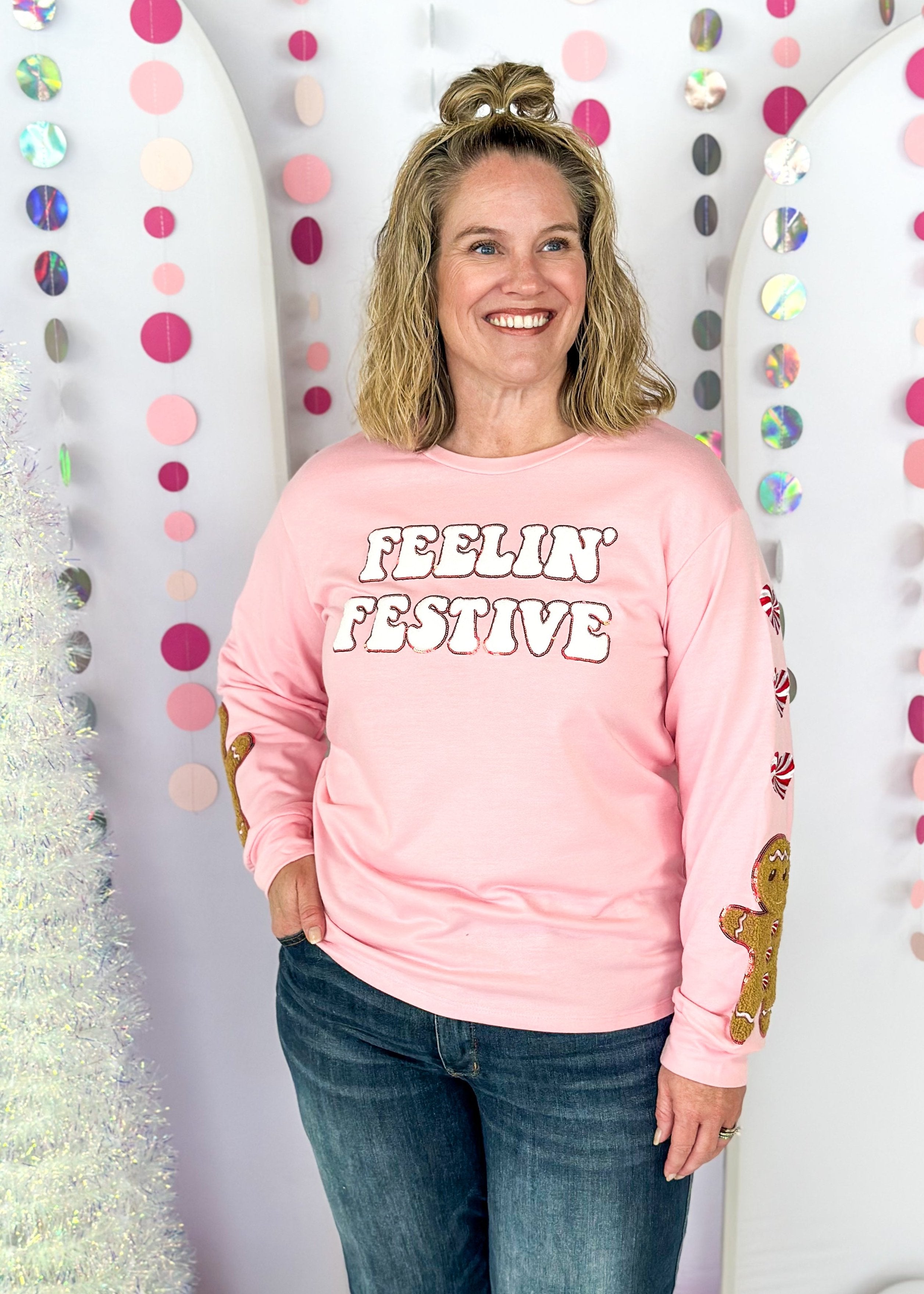 pink long sleeve top with feelin' festive patches across the front - heart shaped peppermint patches down the sleeve with one gingerbread man patch at the bottom of each sleeve