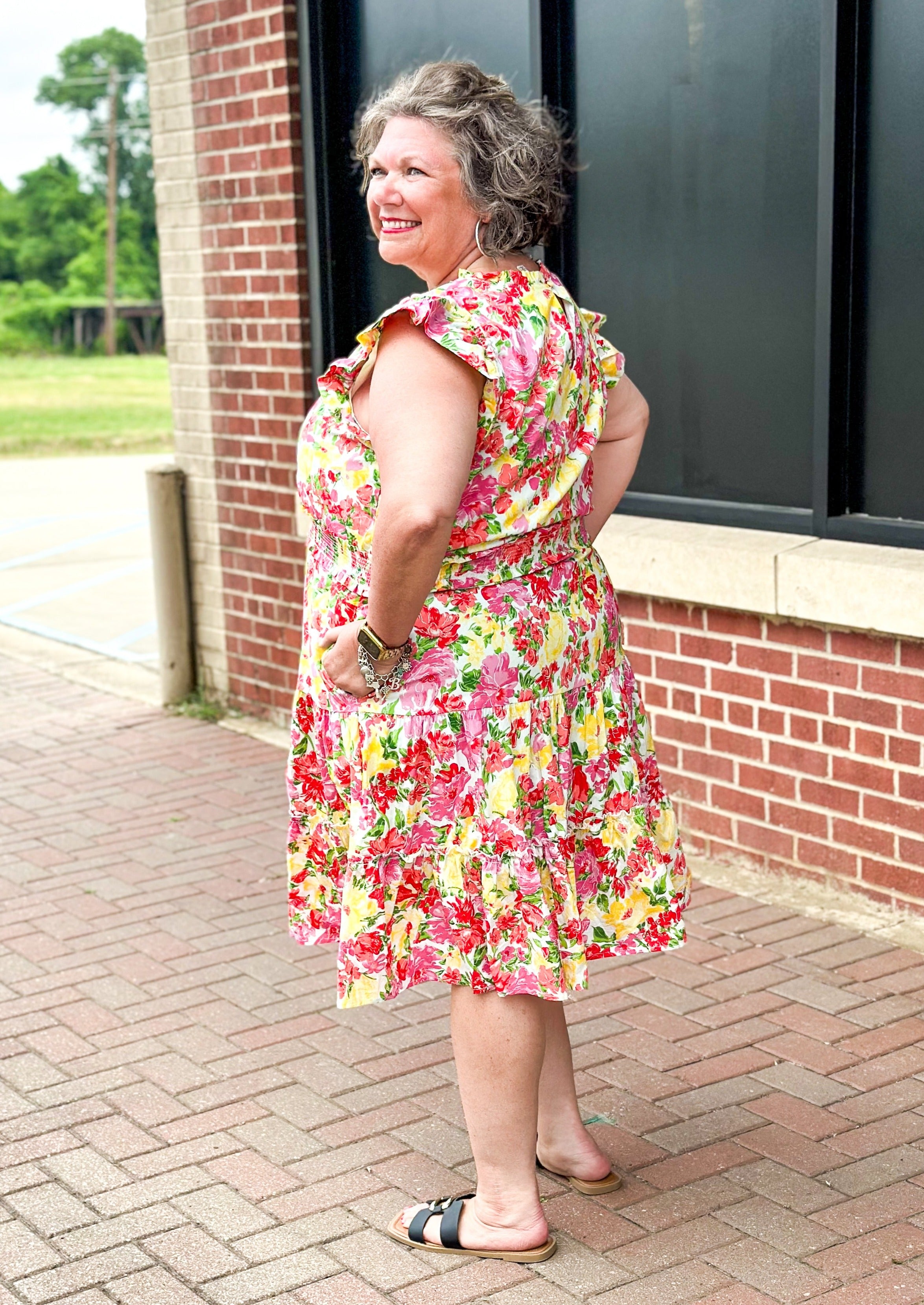 bright floral print smocked waist dress with pockets, ruffle sleeve and neck and one around the bottom  - print colors are yellow, pinks, reds and some green