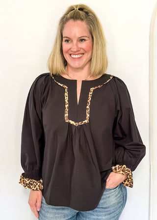 Black long-sleeve blouse with leopard print trim on split neckline and cuffs.