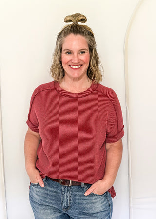 Woman wearing a red sweater and blue jeans against a white background