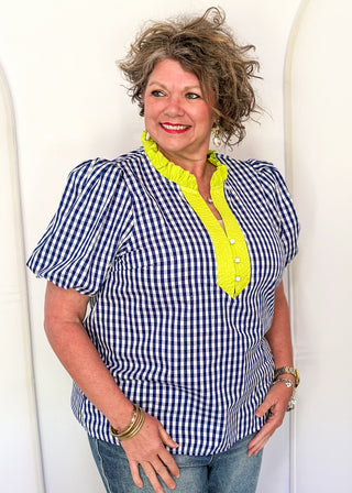 Women’s gingham blouse with decorative buttons and statement neckline detail.