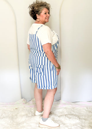 Blue and white striped shorts romper with front pocket and back pockets with heart cut out. 