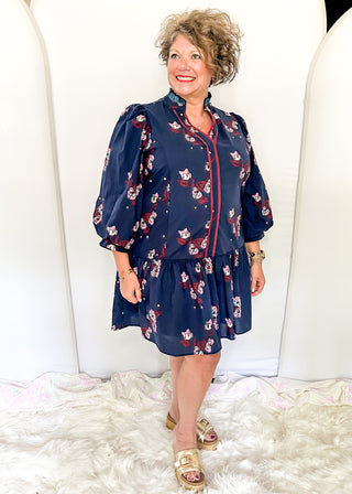 Floral navy dress featuring v-neckline, burgundy piping, and puff sleeves