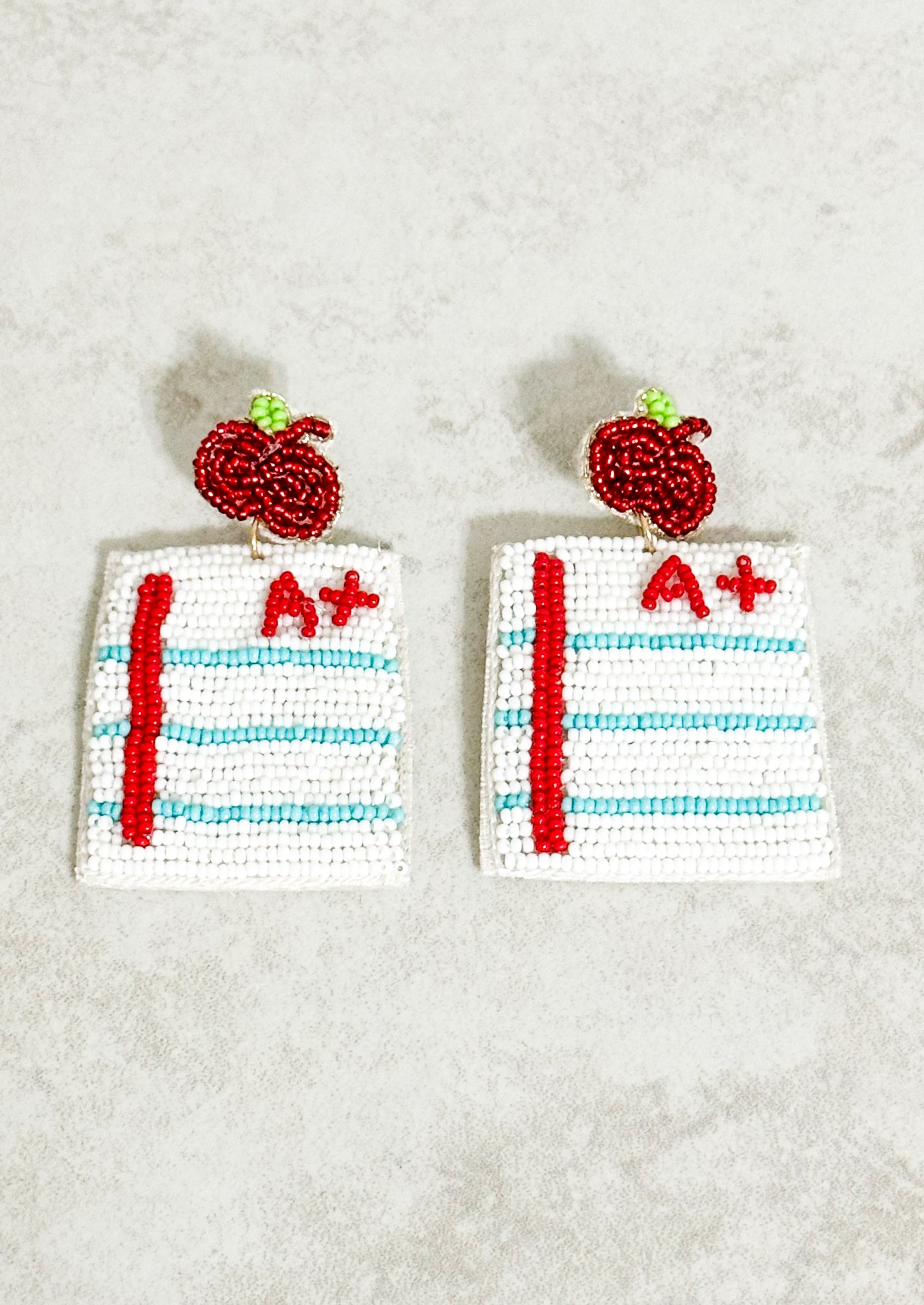 Seed bead earrings that look like a sheet of paper with a red A plus on the top right corner and hanging from a red beaded apple - post back