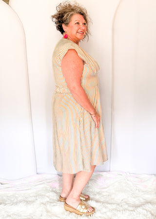 Sleeveless dress with vertical taupe and white stripes. v neck and smocked waist