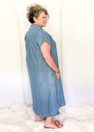 Woman wearing a denim dress standing on a white fluffy rug with a white background
