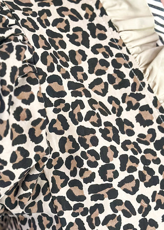 close up of leopard print blouse with ruffle neckline, puff sleeves, and striped trim.