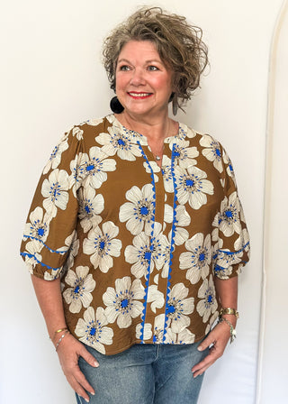 Mocha colored floral blouse featuring white and blue blooms with blue scalloped trim. 