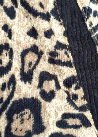 Close-up of a leopard print fabric with beige, black, and brown tones, alongside a dark navy corduroy texture.
