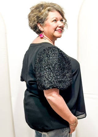black top featuring sparkly sequin puff sleeves and a relaxed, flowy body.