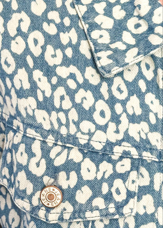 Close up of cropped denim jacket with a blue and white floral print, long sleeves, button-front closure, and chest pockets