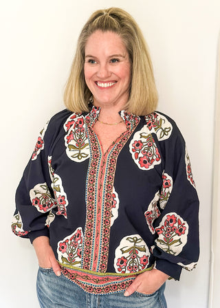 Navy boho print top featuring smocked collar large floral bundles and colorful border trim.
