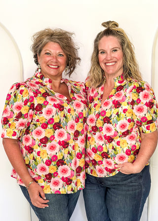V-neck floral puff sleeve top with bright blooms in pink, wine, gold and green. short sleeve, ruffle collar with 3 button closure. 
