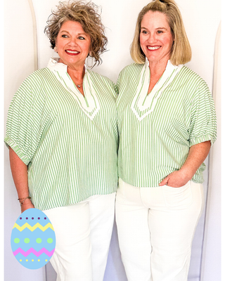 Two women wearing matching green and white striped tops against a white background