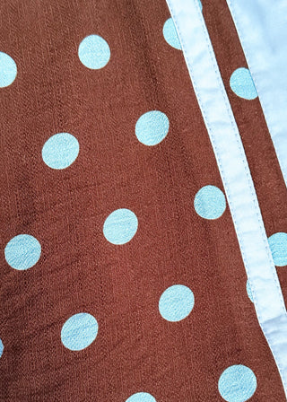 A close-up of a brown fabric item with light blue polka dots and a contrasting light blue trim.