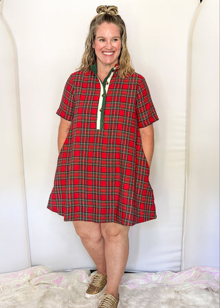 Woman wearing a red plaid dress standing against a white background