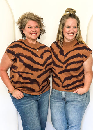 Two women wearing tiger-striped shirts and jeans against a white background