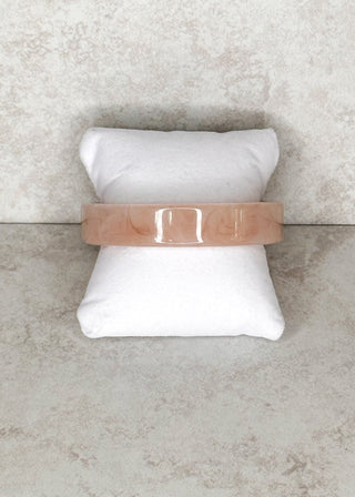 Light blush bangle bracelet displayed on a stand 