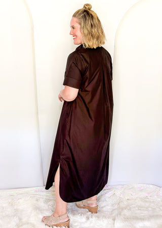 Casual black women’s dress with collared neckline, rolled sleeves, and decorative gold snaps