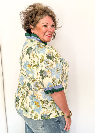 light blue and dark green botanicals on an ecru background.  Short ruffle sleeves, v-neck ruffle collar.  