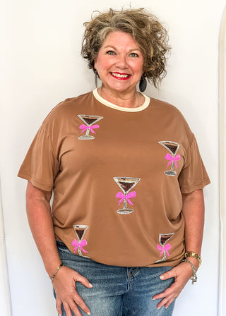 Mocha top featuring sparkling sequin cocktail glasses with pink bows and cream neckline.