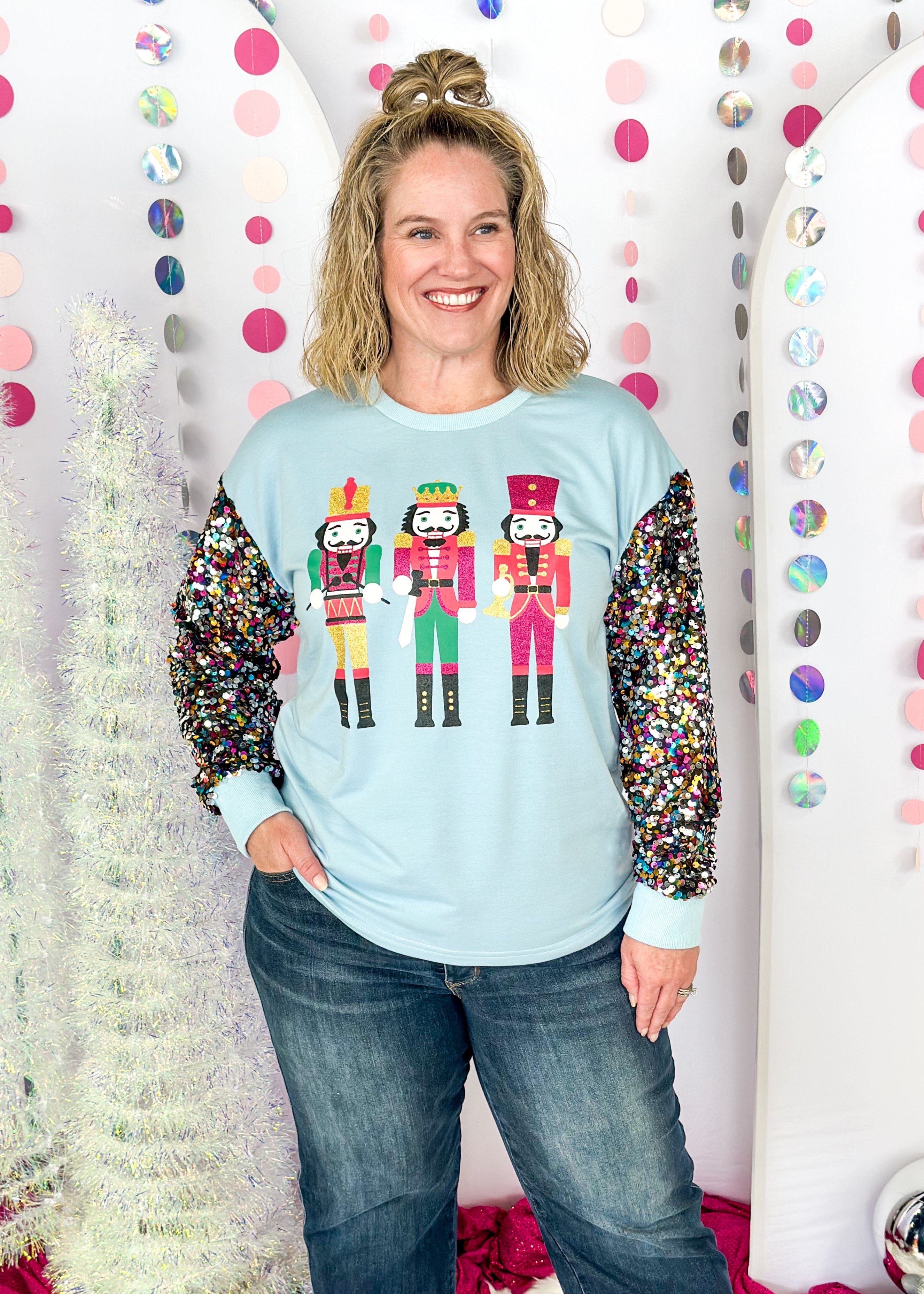 light blue long sleeve top with a trio of 3 sparky nutcrackers on the front and full multi colored sequin sleeve - light blue banding around cuff