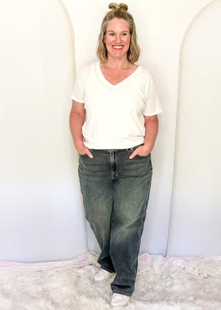 Woman wearing a white t-shirt and blue jeans standing against a white background