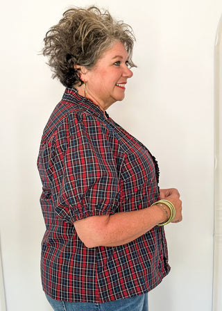 side view of woman wearing a plaid puff sleeve top in dark navy with short sleeves and a V-neckline.