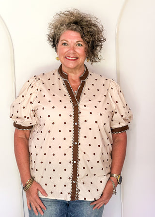 woman wearing Ecru button up top with brown polka dots. 