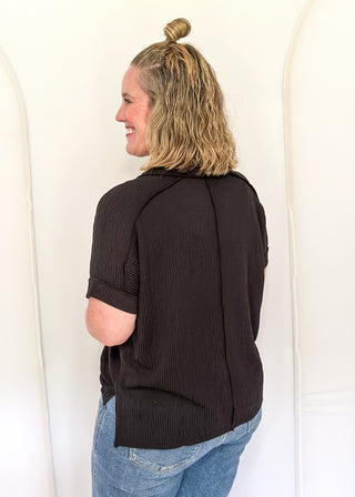 Person wearing a black sweater and blue jeans standing against a white background