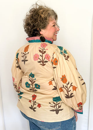 Ecru floral blouse with colorful flowers, contrast turquoise and rose trim, and ruffled neckline