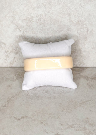Buttermilk bangle bracelet displayed on a stand 