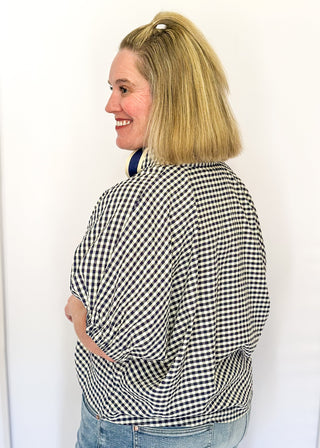 Navy check pattern blouse with contrast white stitching, short dolman sleeves, relaxed shape, and v-split neckline.