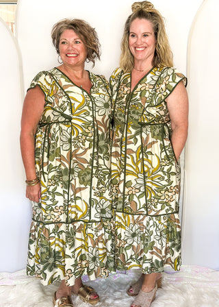 Ruffle cap sleeve maxi dress. off white background with green botanical print.  Dark green piping detail around v-neck, sleeves, bottom tier.  dark green ties on each side of waist. 