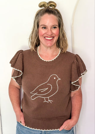 woman wearing brown short sleeve sweater with bird. 