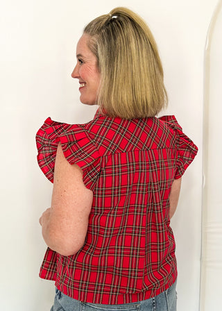 side view of woman wearing red plaid shirt with flutter sleeves