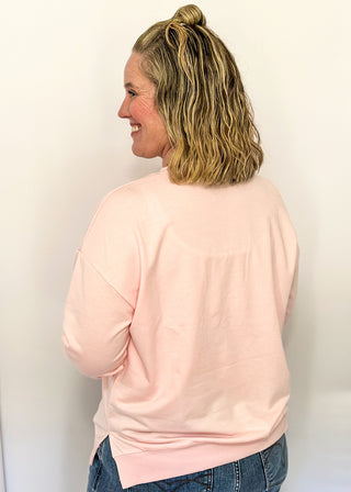 Lightweight pink long-sleeve top with multicolor chenille patch letters spelling “TAKE IT EASY”