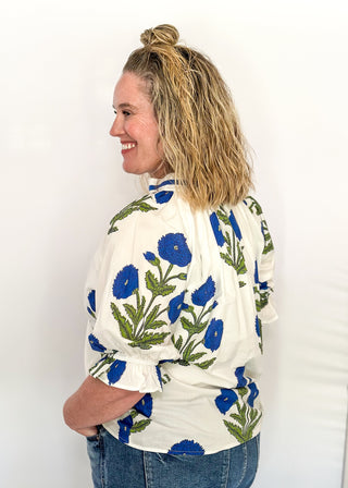 3/4 smocked sleeve white top with large blue blooms. V-neck with blue piping detail. 