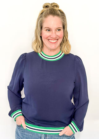 Navy long-sleeve top with green-and-white striped trim at neckline, cuffs, and hem.