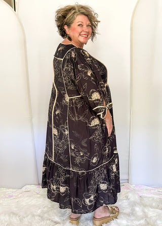 Black midi dress with cream piping and tie details on sleeves and waist.