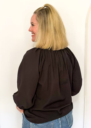 Textured black blouse with leopard lace detail on v-neckline and cuffs.