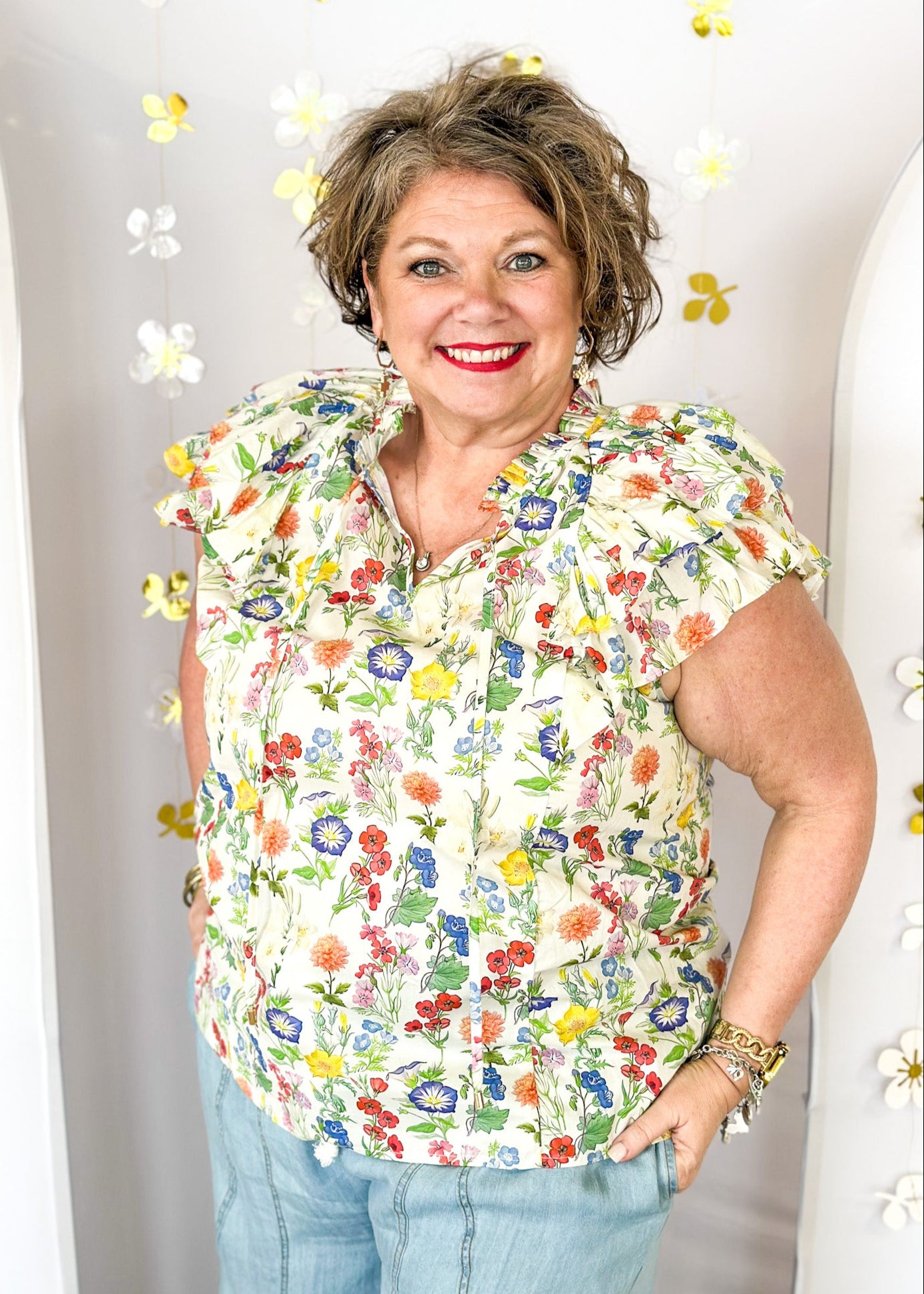 Multi-color wildflower print short sleeve top with ruffle sleeve and tie detail at the neck. 