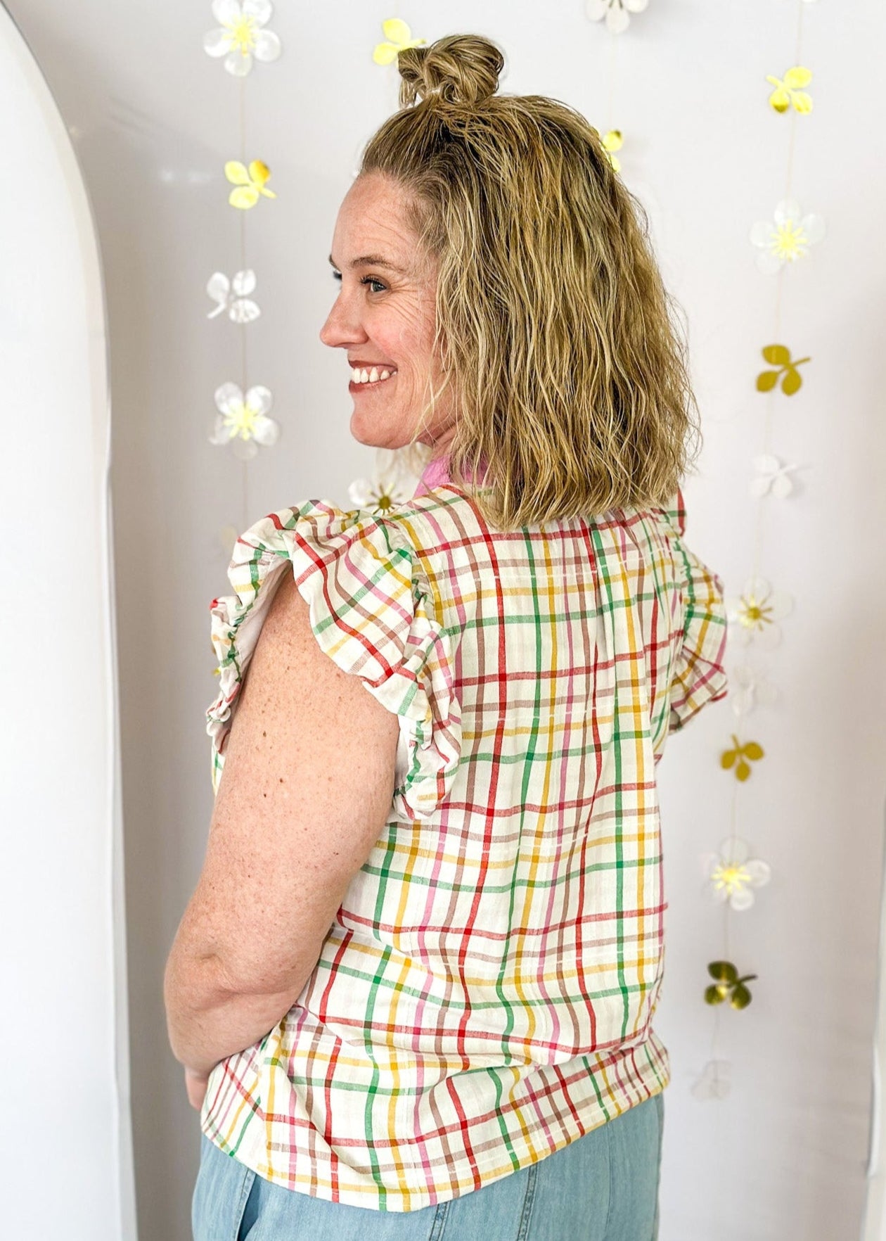 Ivory ruffle sleeve top with red, pink, yellow, and green plaid stripes.  V-neck with solid pink and red scallop detail around the collar and surrounding the v-neck. 