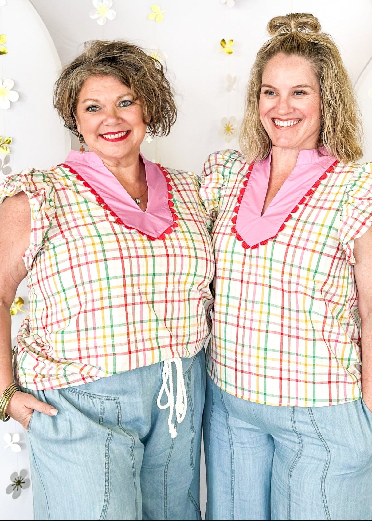 Ivory ruffle sleeve top with red, pink, yellow, and green plaid stripes.  V-neck with solid pink and red scallop detail around the collar and surrounding the v-neck. 