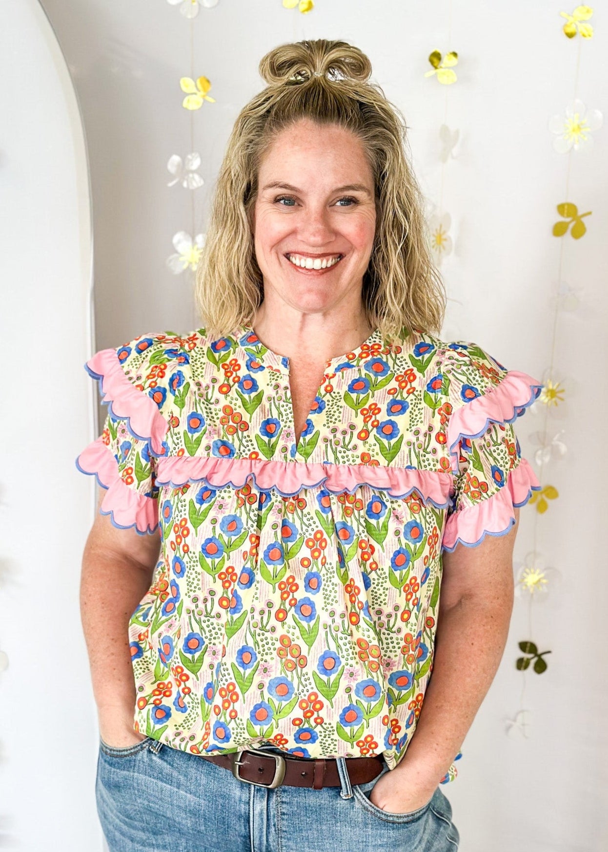 lightweight short sleeve v-neck blouse. Small pink, blue and orange flowers with pink scallop ruffle detail on the sleeve and across the chest. 